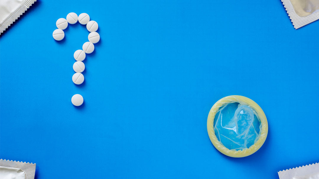 Condoms and a question mark formed with birth control pills against a blue background