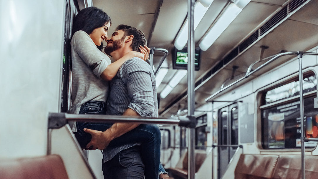 Couple on subway train, woman has legs wrapped around man's waist up against door