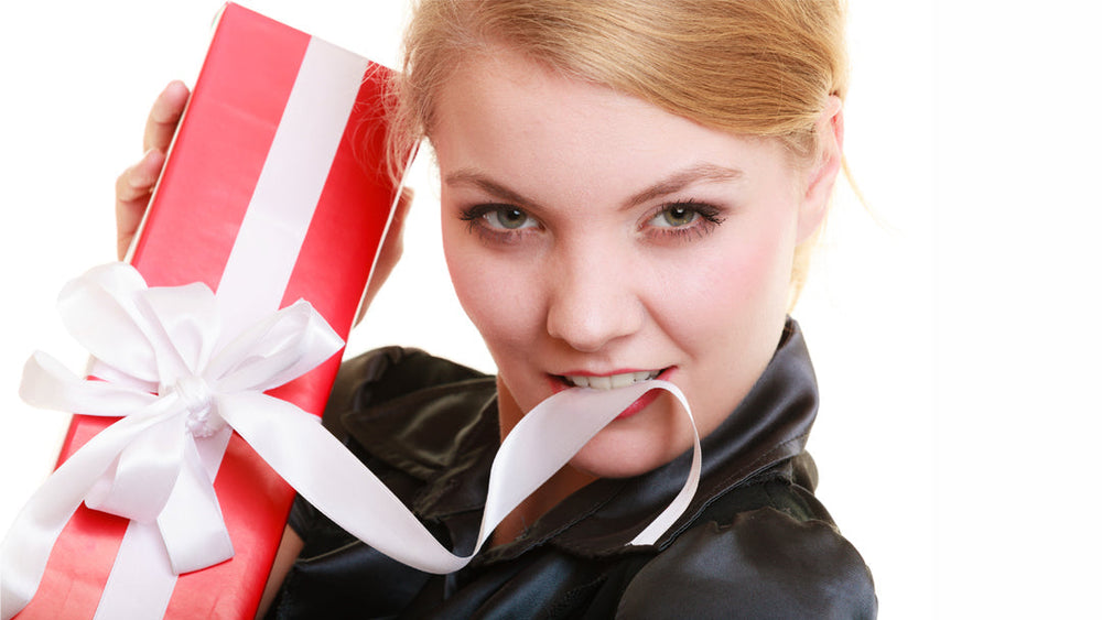 Young woman with wrapped gift, biting ribbon