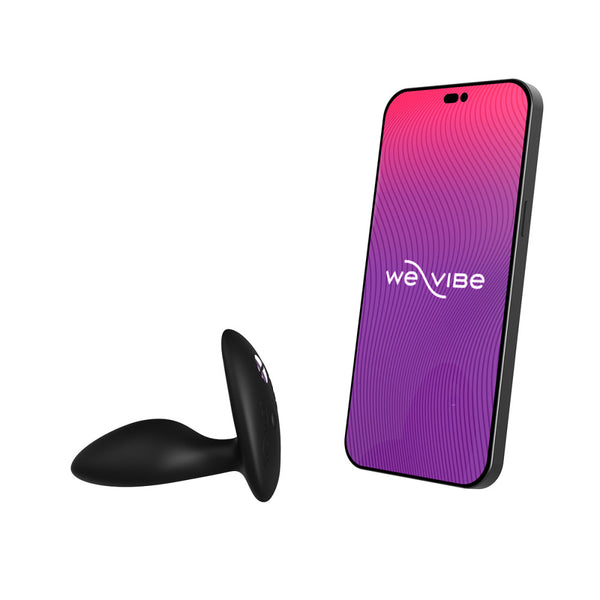 black silicone butt plug shown next to a cell phone screen that has the we-vibe logo. meant to show that the sex toy is app compatible