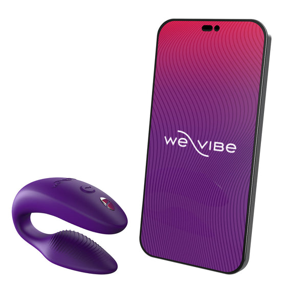 c-shaped wearable sex toy in purple next to a cell phone with a we-vibe logo on its screen. meant to show that the sex toy can be controlled via the phone app