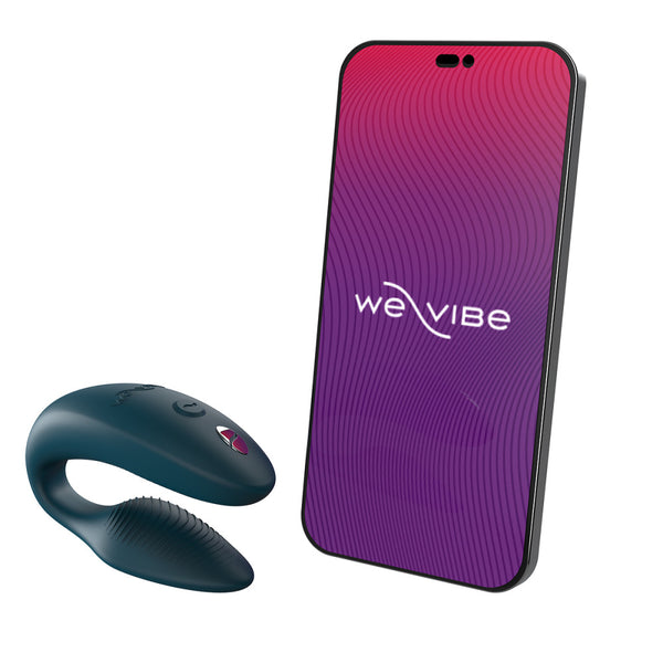 c-shaped wearable sex toy in green next to a cell phone with a we-vibe logo on its screen. meant to show that the sex toy can be controlled via the phone app