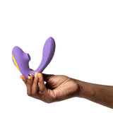 dark brown non-gendered hand with orange nail polish holds the romp reverb dual stimulation toy showing the air pulse nozzle and internal shaft