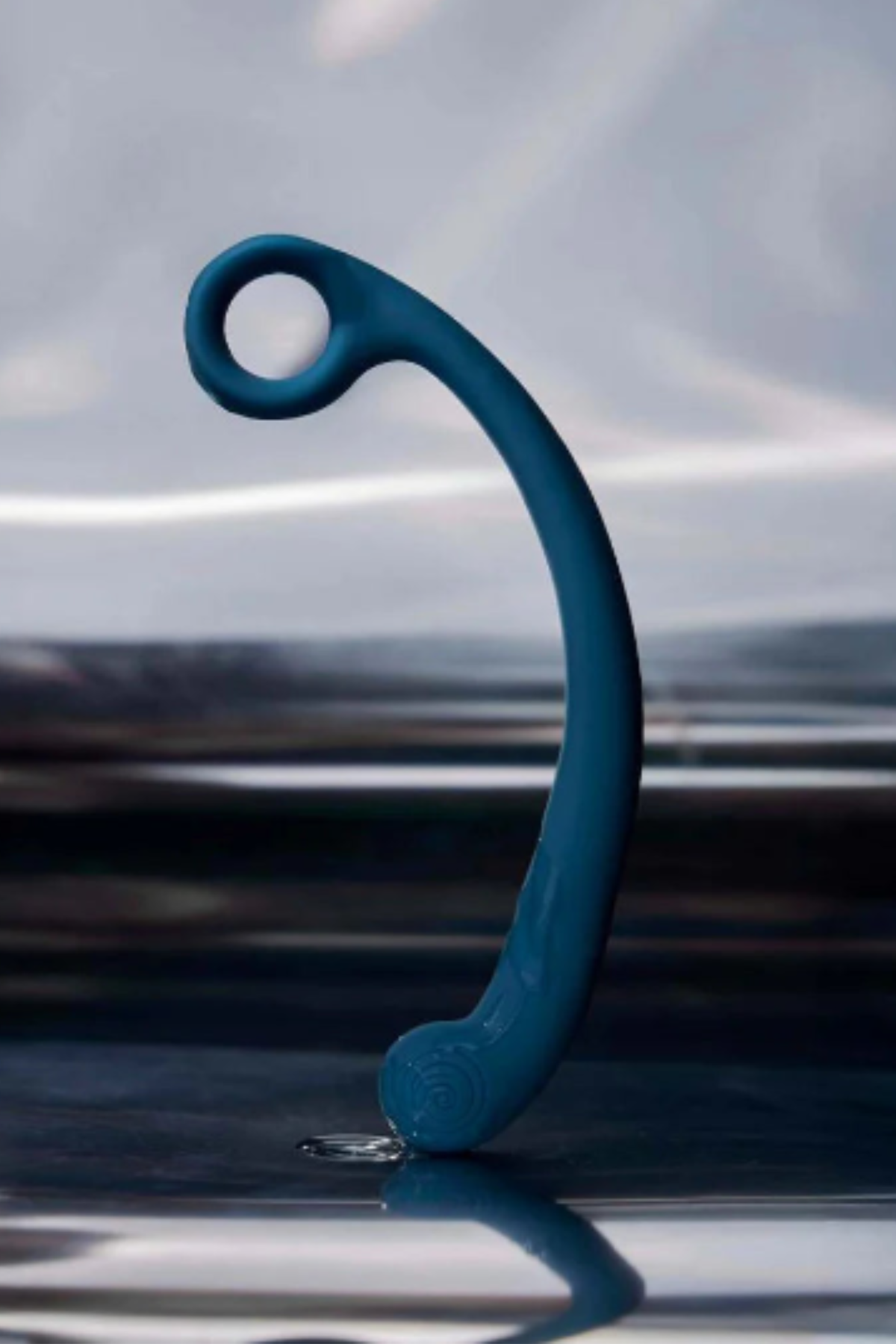 Blue Lagoon Axi Slimline G-spot wand standing on its tip on a reflective wet surface, showing that this vibrating wand is fully waterproof