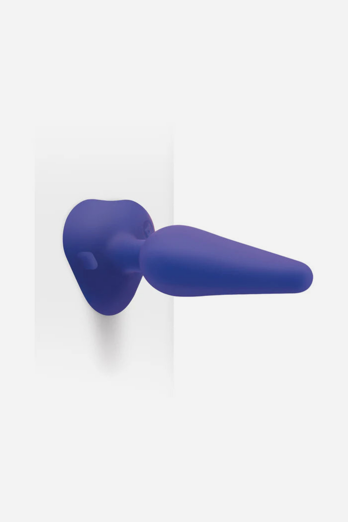 Navy B-Vibe training plug stuck to a wall by its strong suction base, showing how the plugs can be used hands-free in different positions
