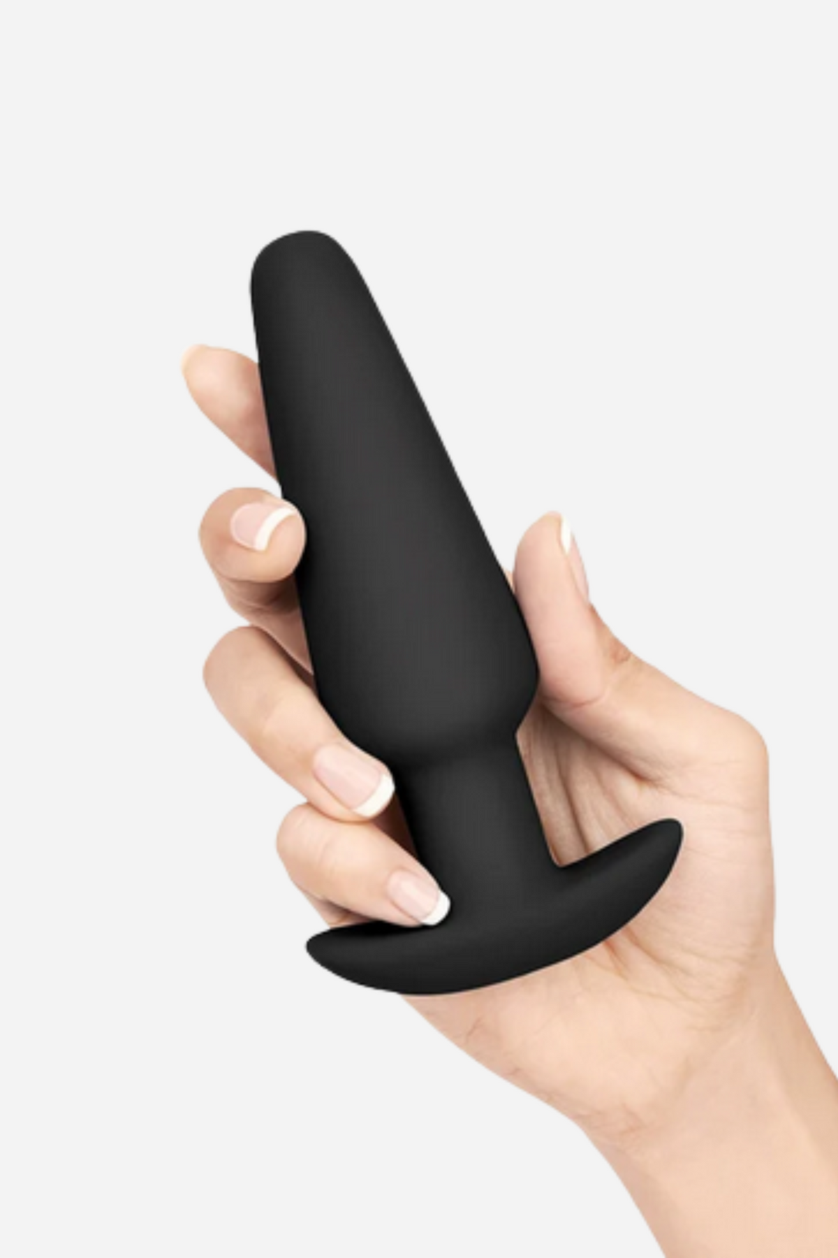Close-up of a hand gripping the large B-Vibe anal training plug in Black, showing its size and smooth flared base on grey