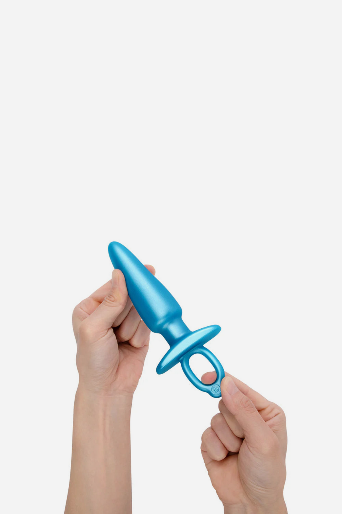 Hands squeezing the blue B-Vibe Butties sleek tapered plug to show how soft and flexible its smooth silicone shaft is, on a grey background