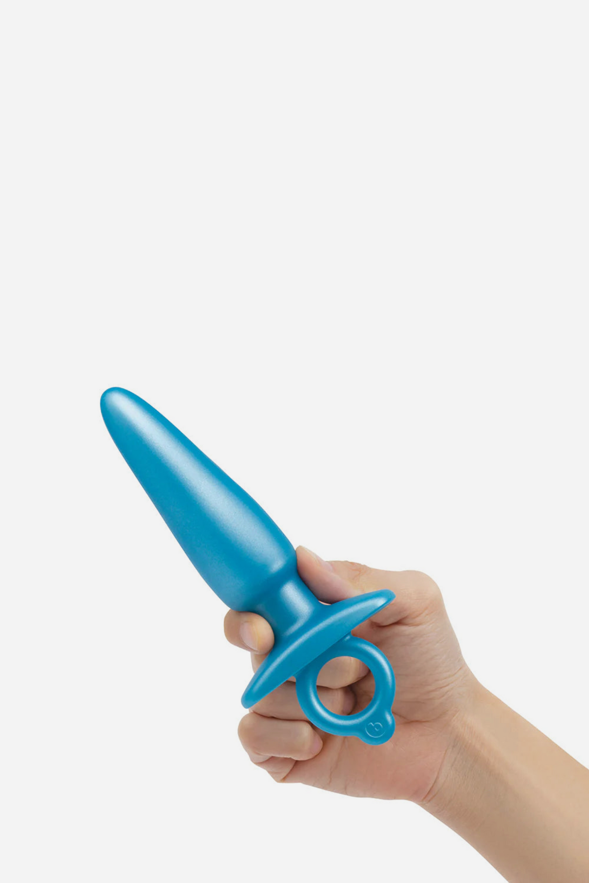 Hand holding the blue B-Vibe Butties sleek tapered plug by its finger ring, showing the tapered shaft and compact size, on grey