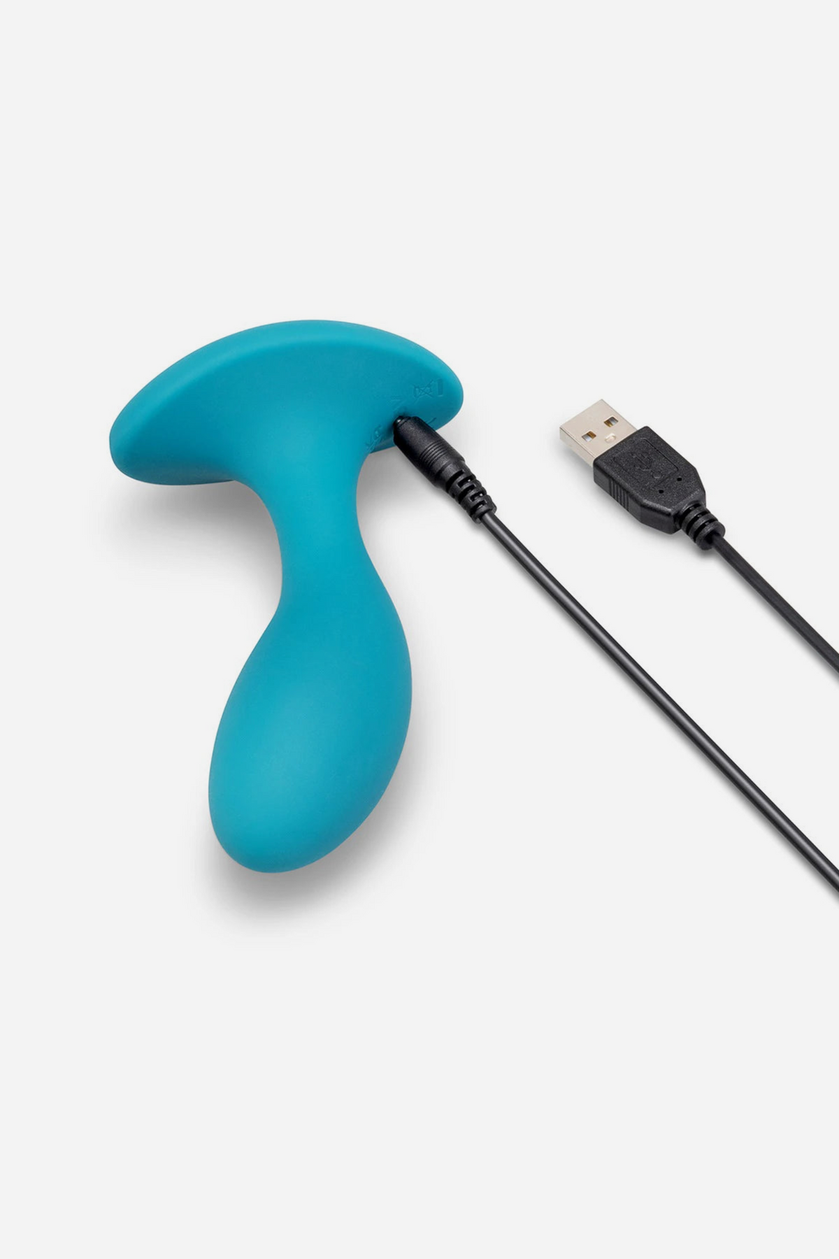 B-Vibe Essentially Speaking large vibrating plug in teal with its USB charging cable attached to the flared base, on a light grey background