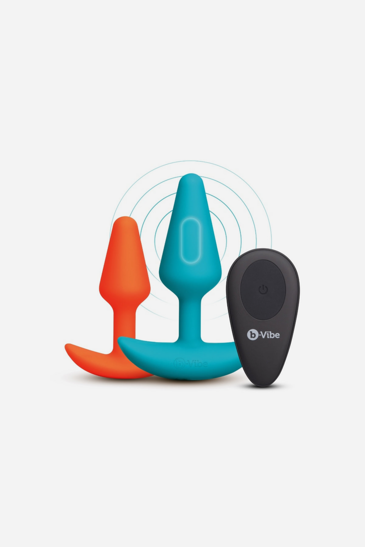 B-Vibe Intro Anal Training Kit with the orange beginner plug, teal vibrating plug and black wireless remote standing upright, on grey
