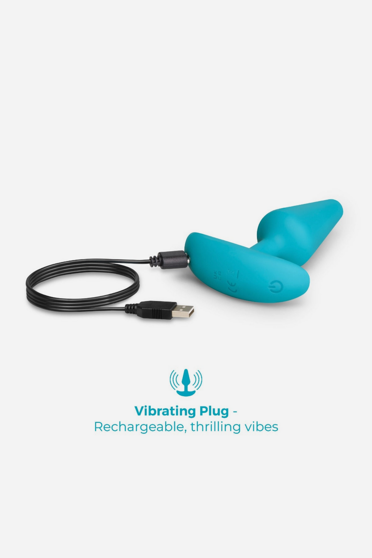 Teal vibrating plug from the B-Vibe Intro Anal Training Kit attached to its USB charging cable, showing it is rechargeable, on grey