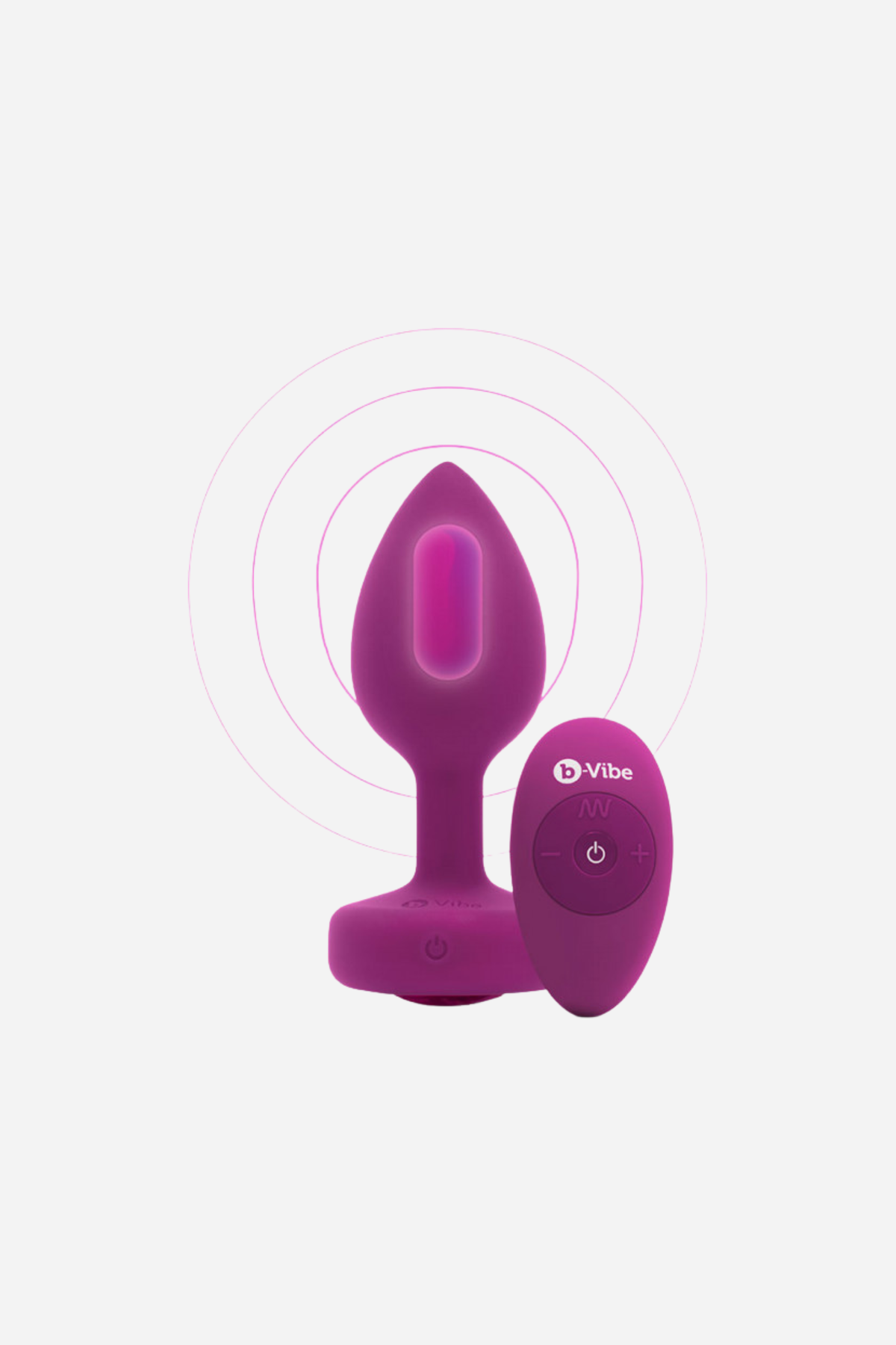 Pink B-Vibe Vibrating Jewel Plug standing upright beside its wireless remote, with a sparkling gem base and vibration rings on a soft grey background