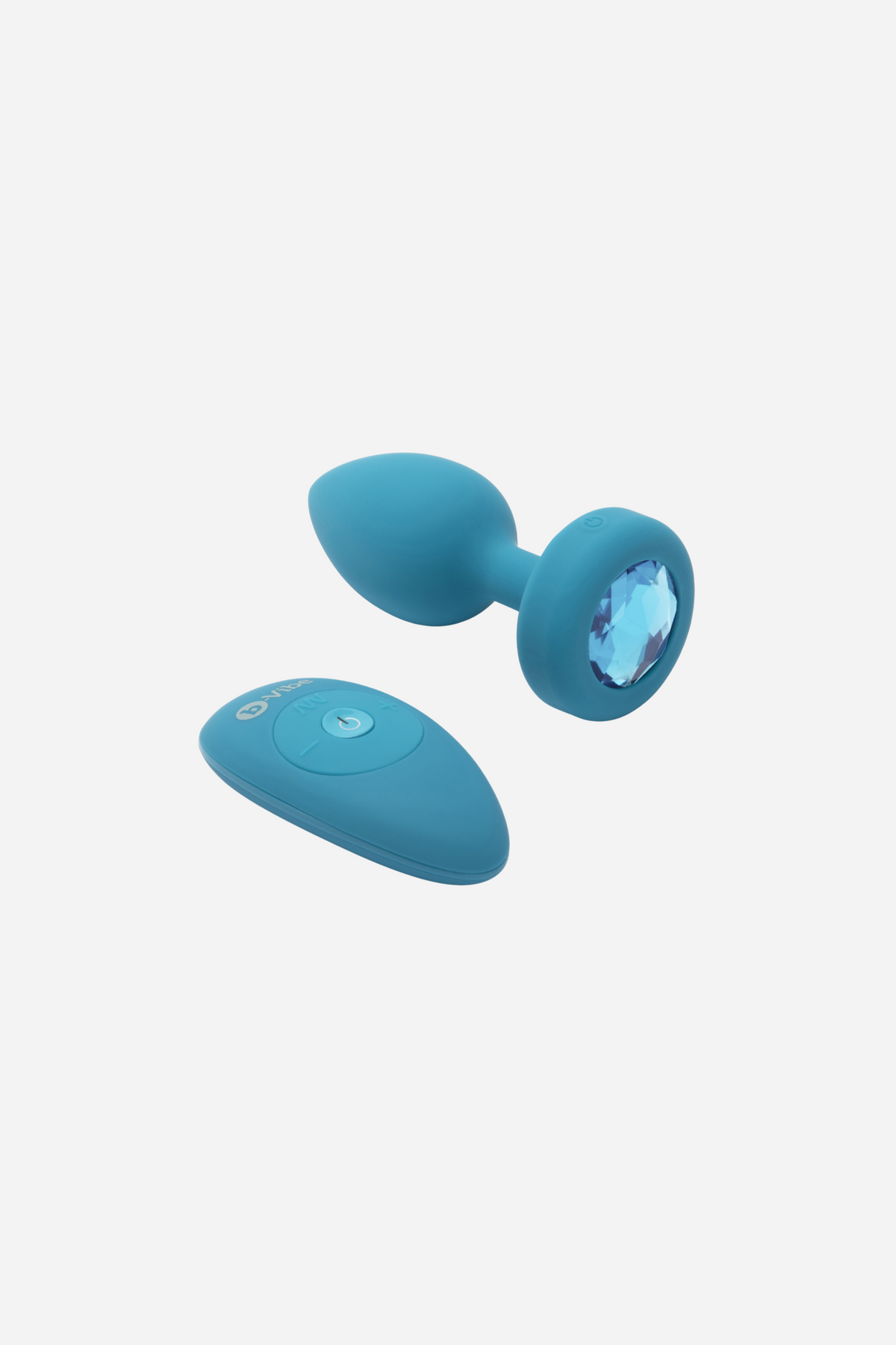 Aqua B-Vibe Vibrating Jewel Plug lying beside its matching wireless remote, a small rechargeable silicone butt plug with a blue jewel base