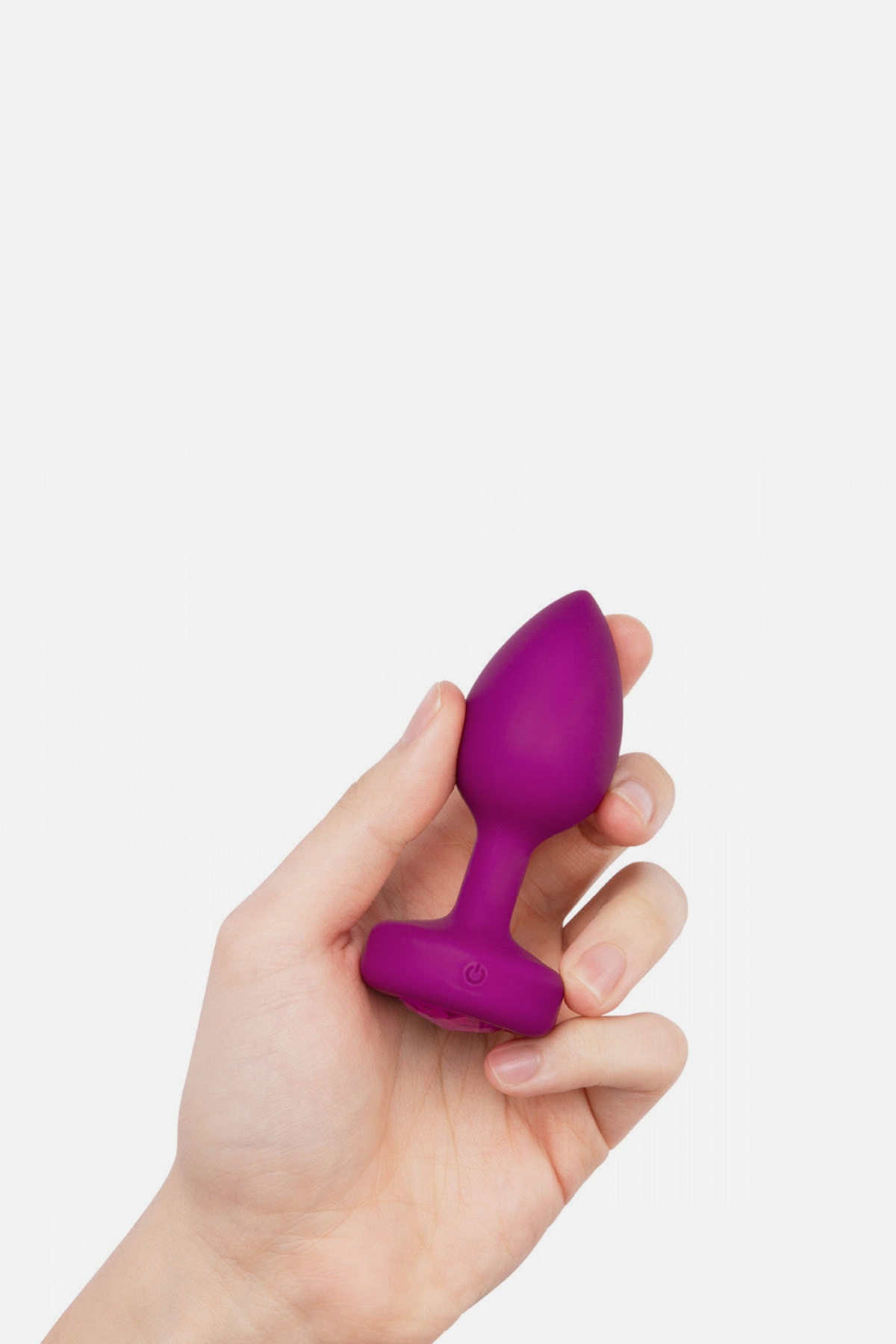 Hand holding the pink B-Vibe Vibrating Jewel Plug to show its small size, tapered silicone tip and sparkling gem on the flared base