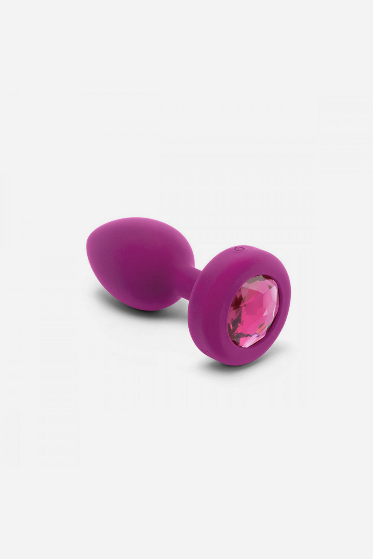Pink B-Vibe Vibrating Jewel Plug lying on its side, showing the faceted gem set into the flared base and the smooth tapered silicone body
