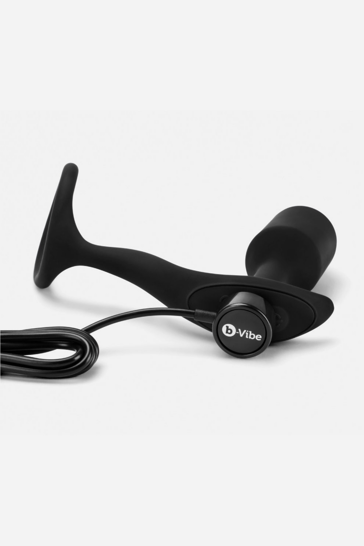 Black B-Vibe Vibrating Snug and Tug cock ring plug connected to its USB charging cable at the base of the vibrating plug, on grey