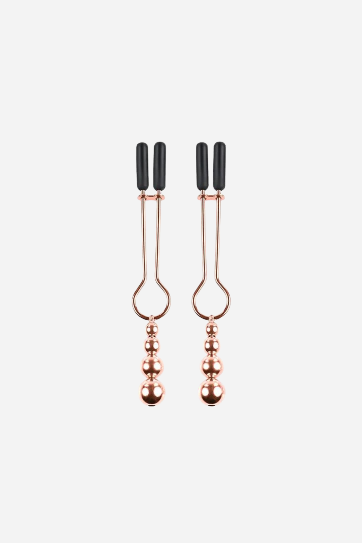 Pair of rose gold tweezer-style nipple clamps with black rubber tips and beaded ball pull weights hanging below, on light grey