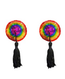 pride pasties feature a circular shape with colorful rainbow pattern of red, orange, yellow, green, blue, and pink sequins. playful black tassels hanging from the center