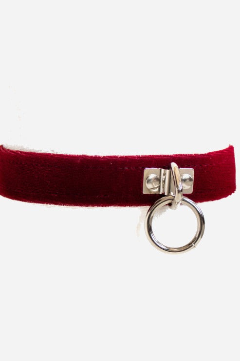 Front of the burgundy Caress velvet collar with a silver O-ring hanging from a riveted chrome tab, the band running off both sides of the frame