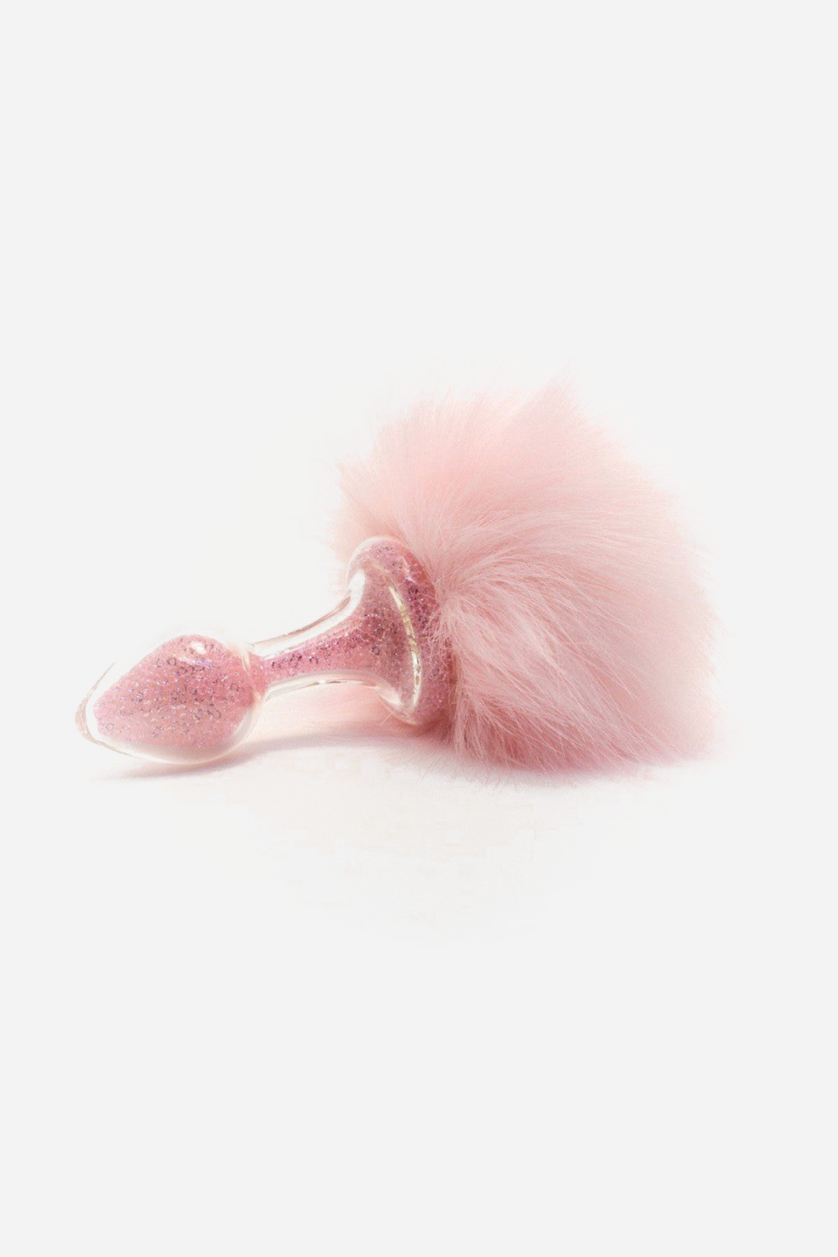 Close side view of the pink glitter glass Crystal Sparkle Plug on grey, its tapered bulb and narrow neck meeting a soft, full pink faux fur tail.