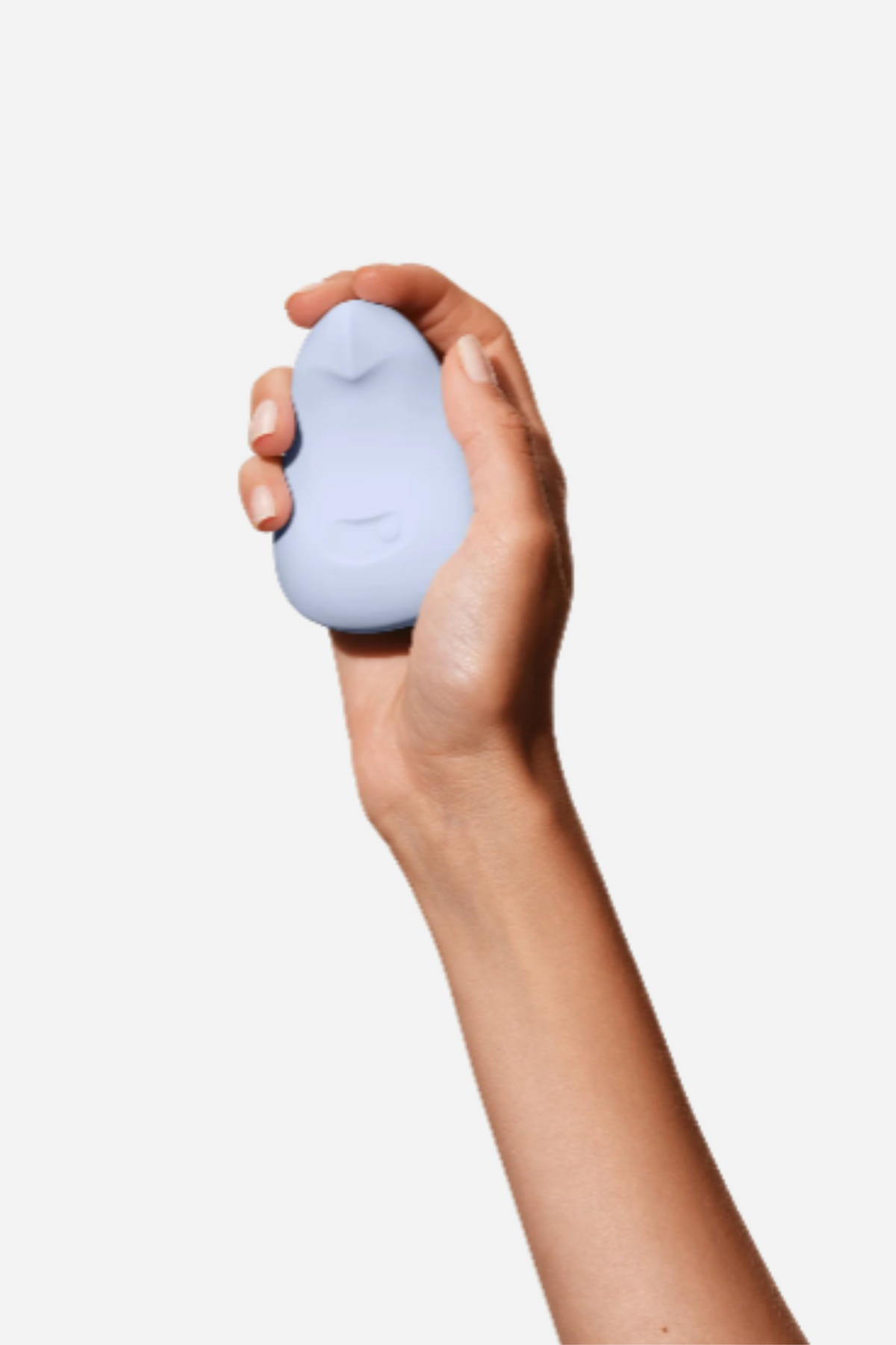 Raised arm holding the ice blue Dame Pom Flexible Palm Vibe, showing how the compact rounded toy sits neatly cupped in the palm of the hand