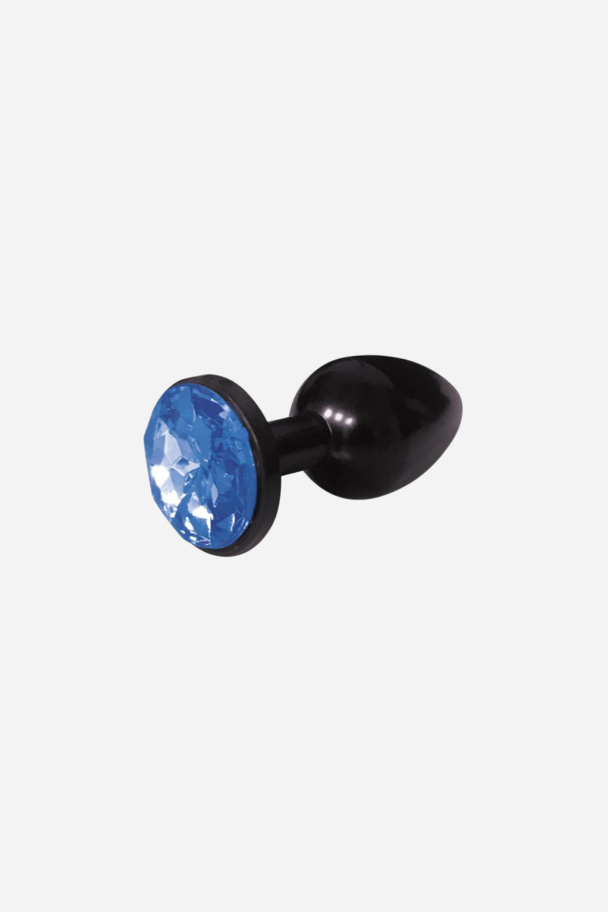 A small black metal butt plug lying on its side with a round faceted cobalt blue gem set in its flared base, on a plain grey backdrop.