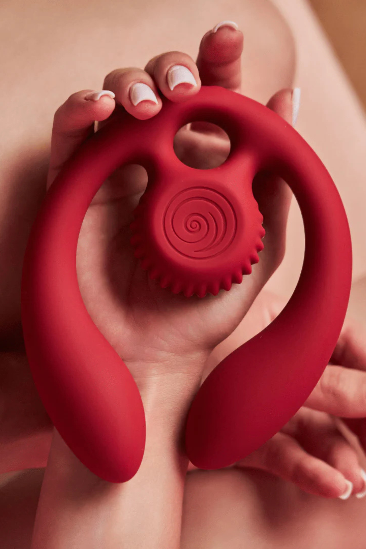 Hands cradling the burgundy Gizi Duo against warm skin tones, showing the size of the snail head and flexible arms in a real hold
