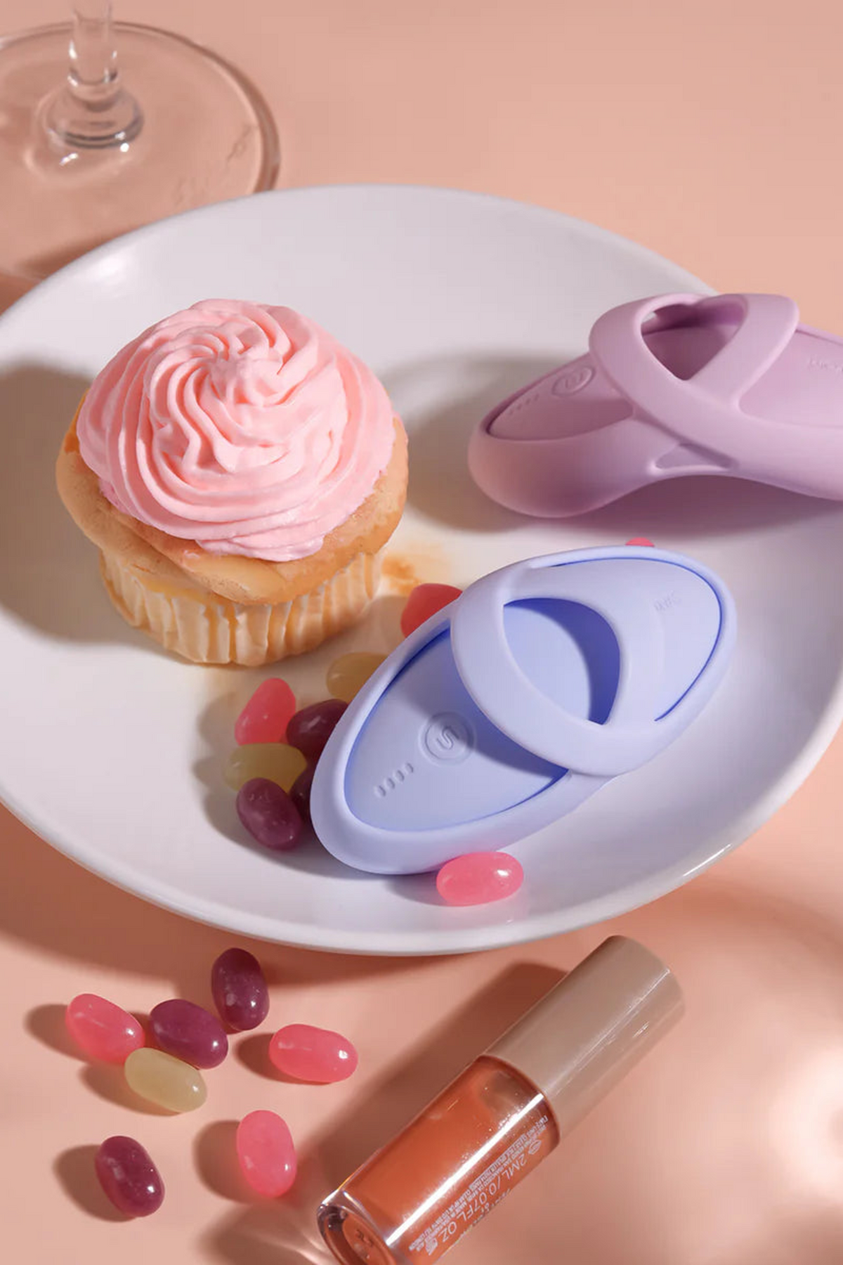 Both colours of the Echo 2 arranged on a plate beside a pink cupcake, lip gloss and scattered petals in a soft pink flat lay.