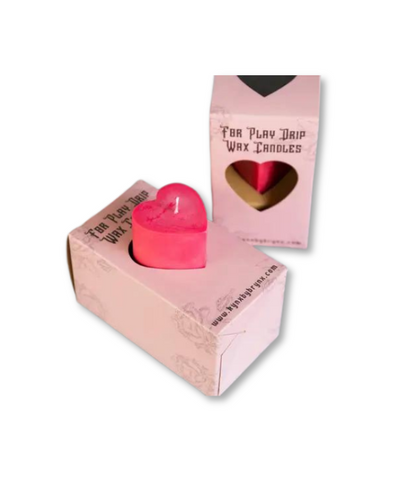 heart pillar shaped wax play candle sits in it's box. demonstrates how the box is used as a holder to catch drips
