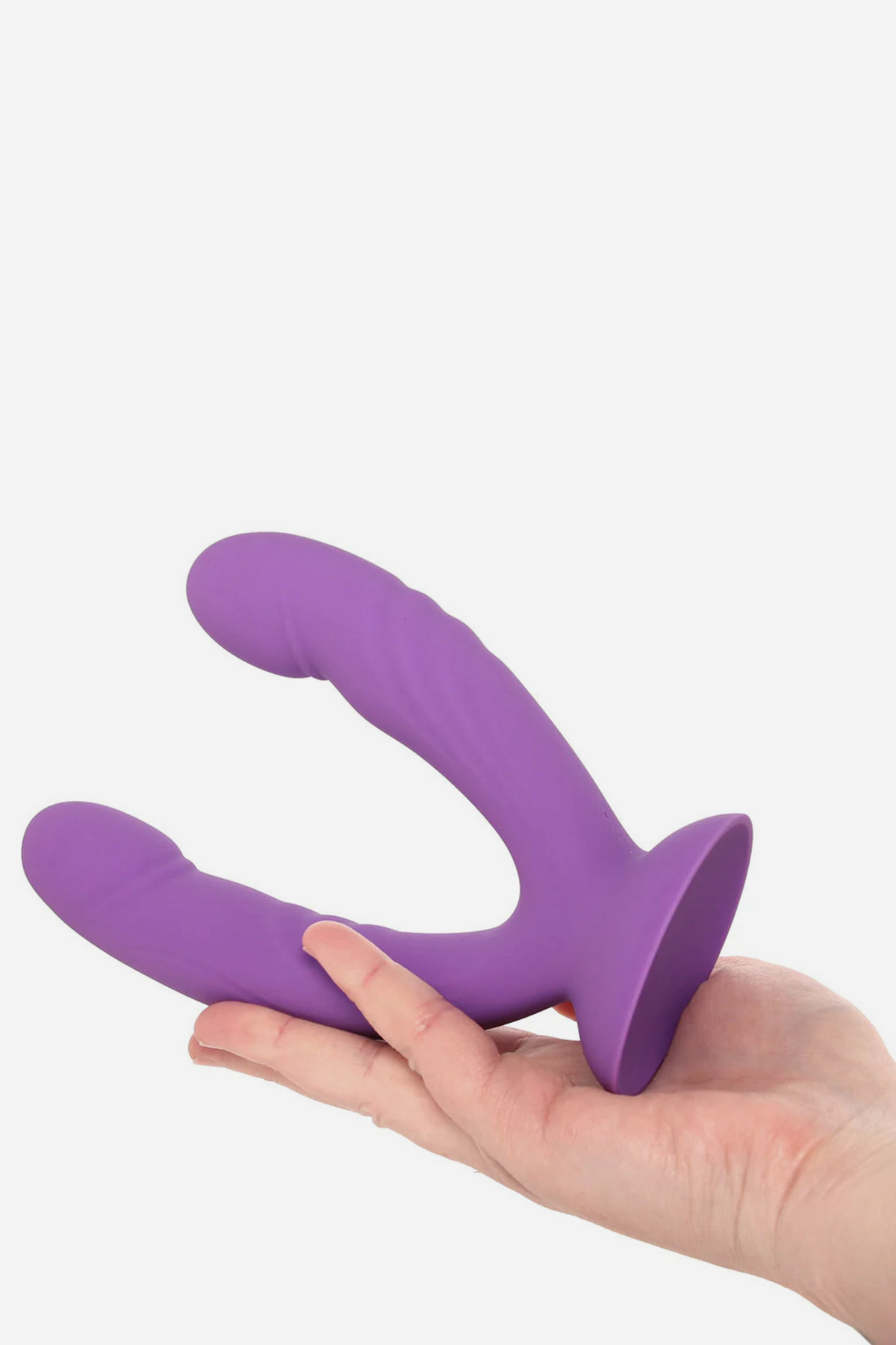 Hand supporting the Get In Ya Vibrating Grinding Dual Dildo by its suction cup base, with both purple shafts pointing outward