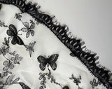 close up of the black embroidery with butterflies and flowers and eyelash lace trim