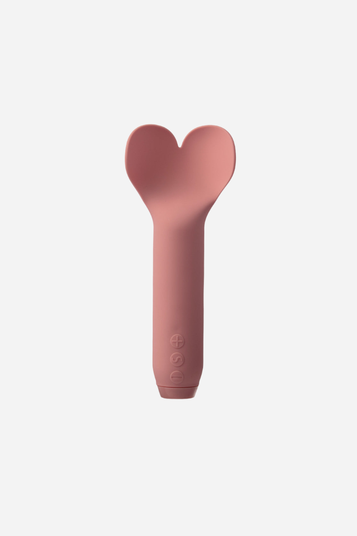 Je Joue Amour flutter bullet in dusty rose on grey, a smooth handle rising to a soft heart shaped head with a dip in the middle.