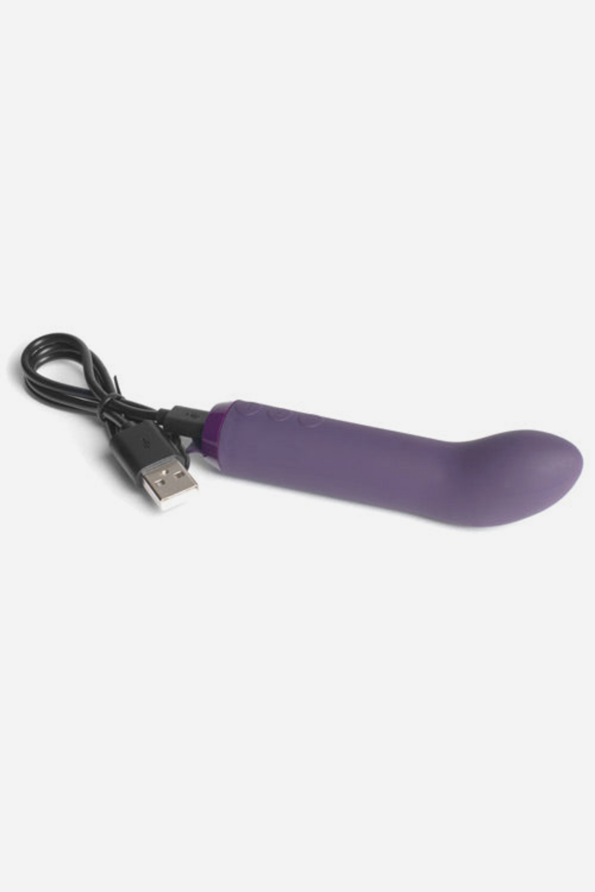 Je Joue G-spot bullet vibrator in Purple with its USB charging cable connected at the base, shown on a light grey background