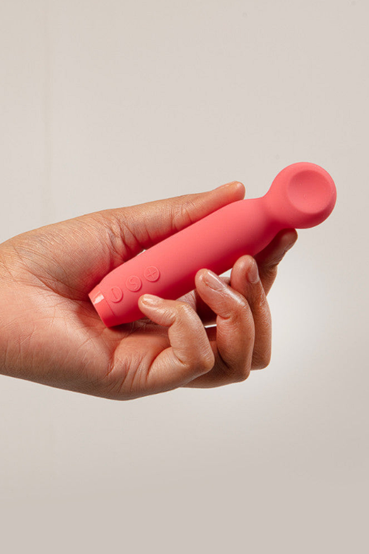 Hand holding the pink watermelon Je Joue Vita Lipped Bullet against a soft beige backdrop, showing its compact, easy-to-grip size