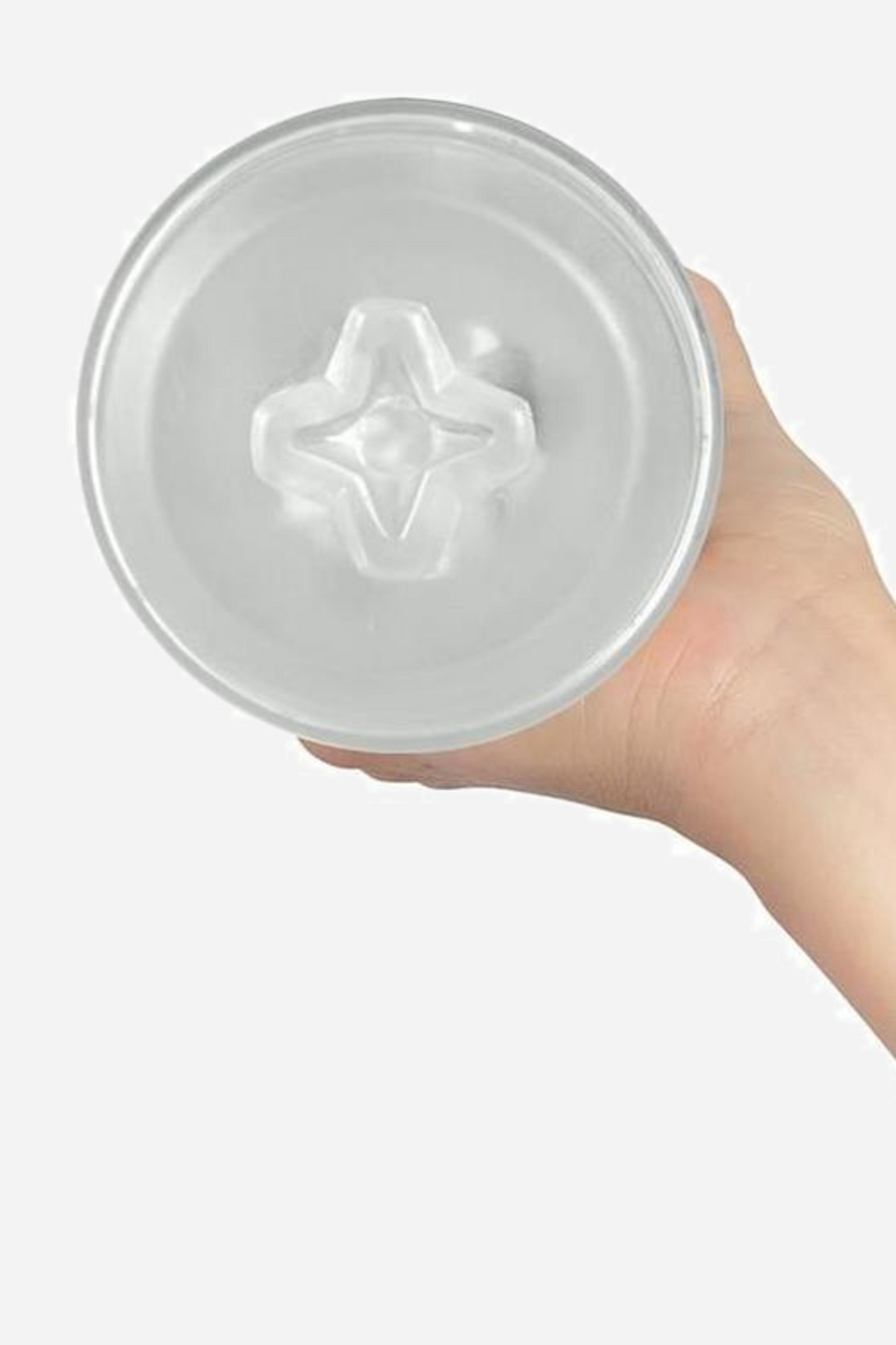 A hand holding the clear Crystal Pocket Feel stroker upright, its open end facing the camera to show the star-shaped textured entry.