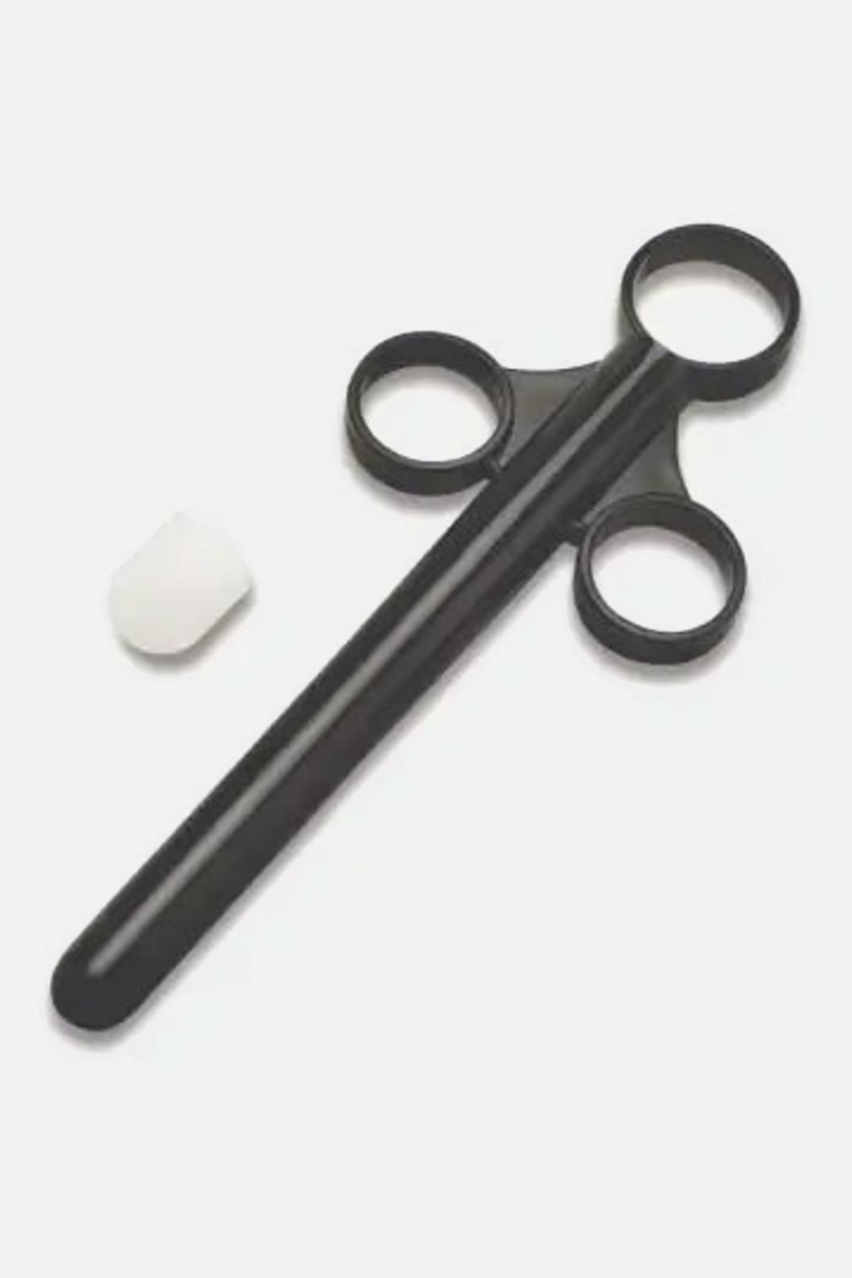 Black plastic lube shooter applicator shaped like a syringe with a long slim barrel and three finger rings, shown beside its small white cap.