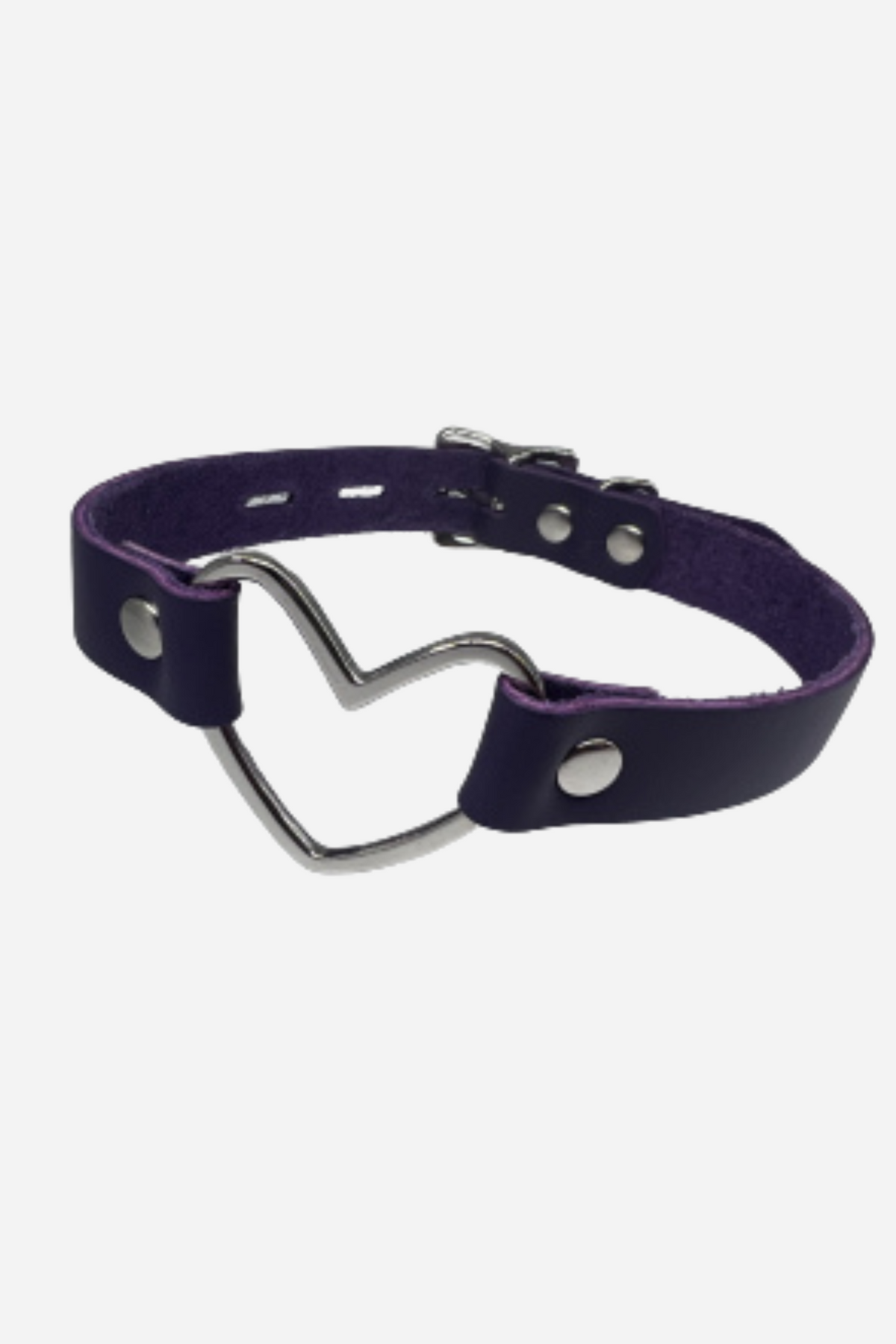 A purple leather collar laid out in a curve, a silver heart shaped ring set at the front between two rows of polished silver studs.