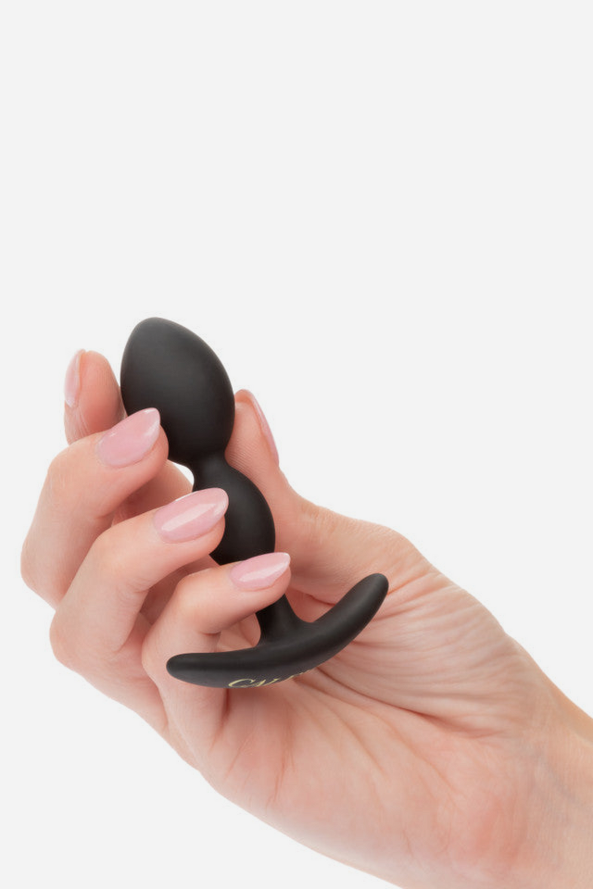 Hand holding the black No Bounds Dual Drop plug between the fingers to show its compact size and flexible curved base, on grey