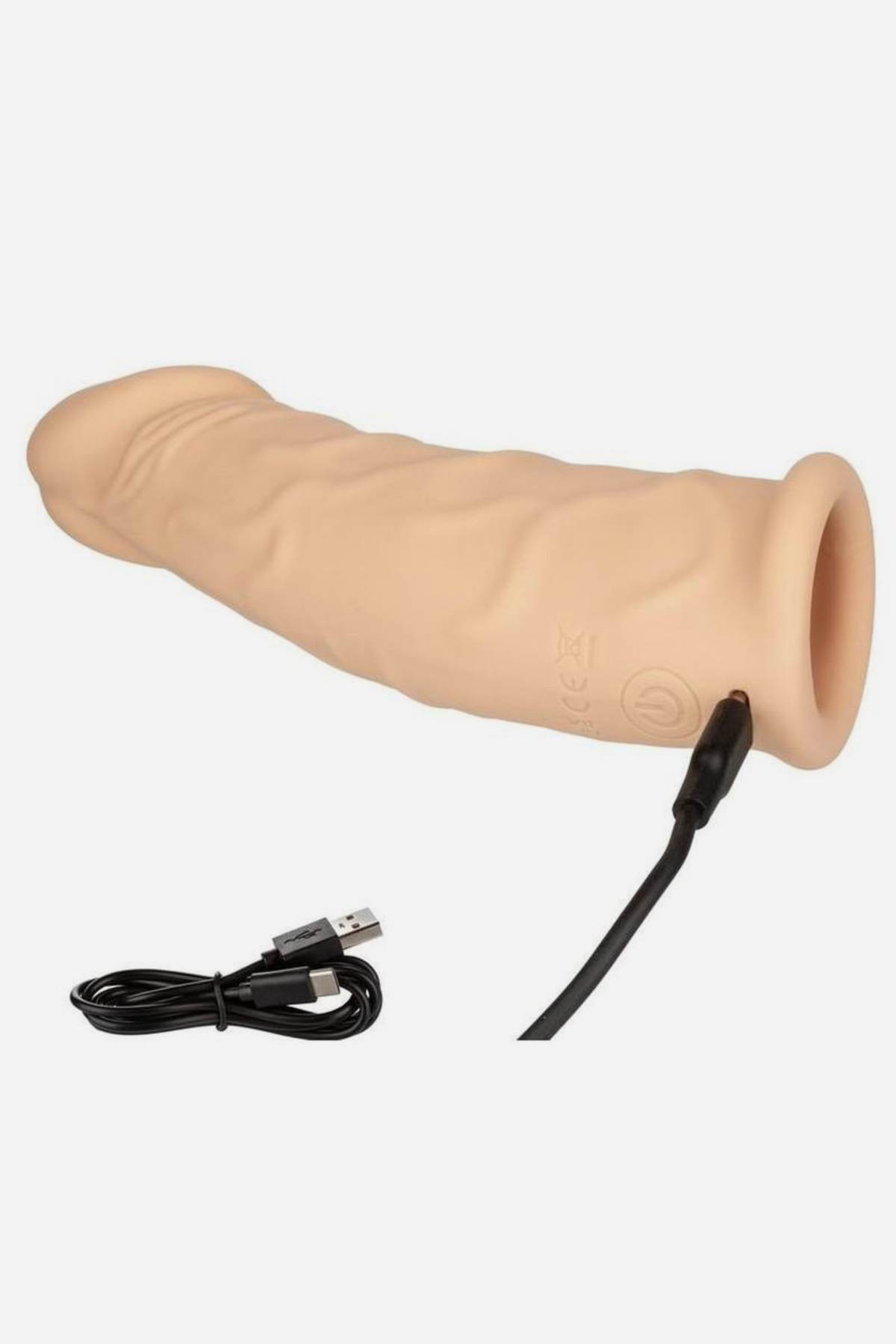 Performer Seven vibrating penis extender in Vanilla lying on its side with the USB charging cable plugged in, showing the open sleeve end