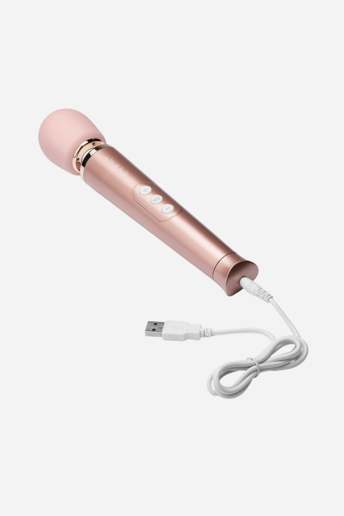 Rose gold Le Wand Petite with its white USB charging cable plugged into the base, showing the rechargeable cordless design on light grey