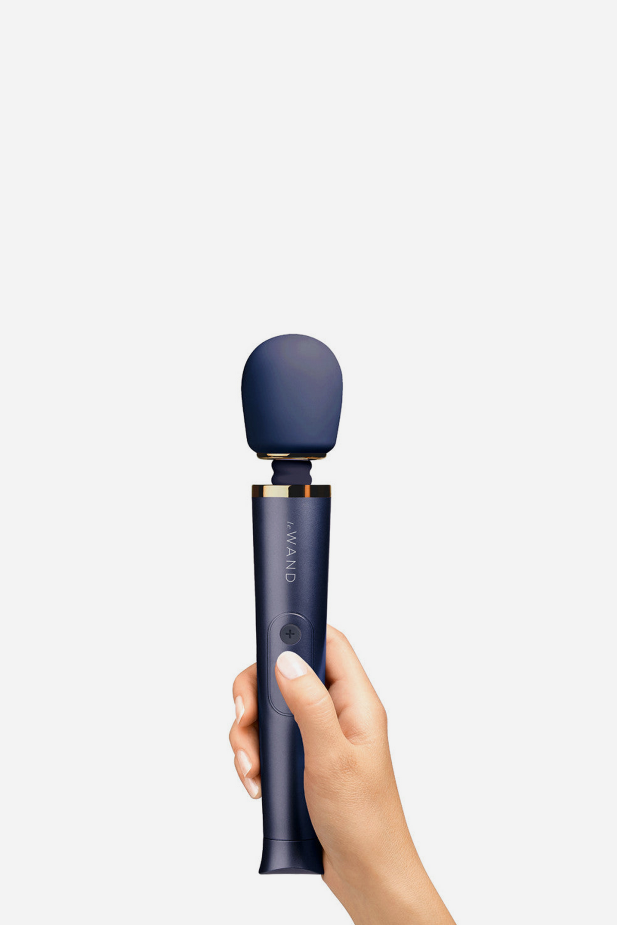 Hand holding the Le Wand Petite massager in navy upright, showing the deep blue silicone head and matching metallic handle on light grey