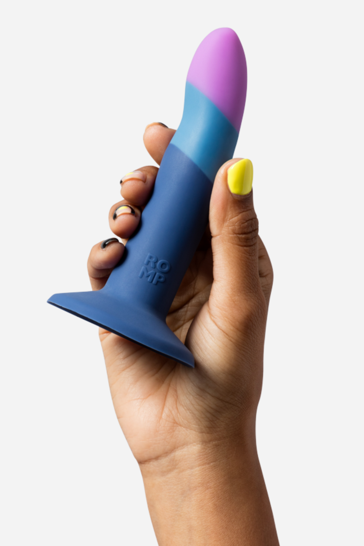Piccolo pegging dildo in Small held upright in a hand, showing the pink tip, light blue and navy colour bands and suction cup base on light grey