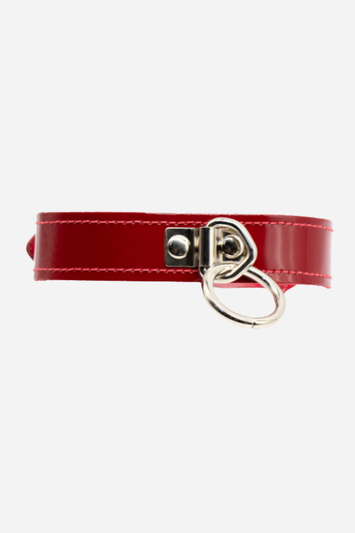A close view of the red patent collar's front, with a large silver O-ring hanging from a riveted keeper on the glossy red strap.