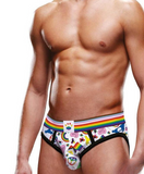 shirtless white male model faces camera to show off the art and of the pride graphics across the front of the briefs. the art includes an intersectional pride flag, hears, rainbows, rainbow peace signs, and a progress pride flag waistband.