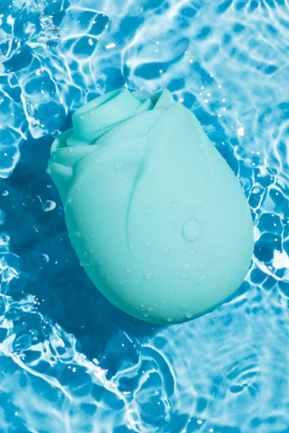 Aqua Romp Rose 2.0 Air Pulsation Toy resting in rippling blue water, showing it is fully waterproof for bath and shower play