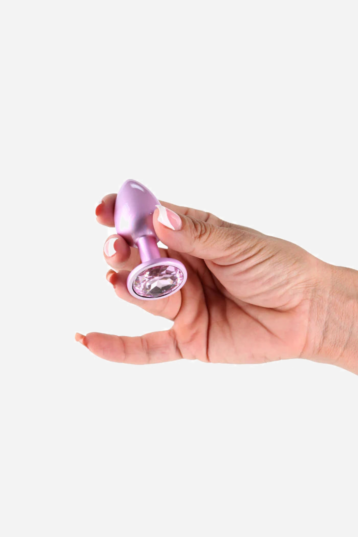 A hand holds the Shimmering Princess plug between two fingers, turning the base so the clear jewel set into it catches the light.