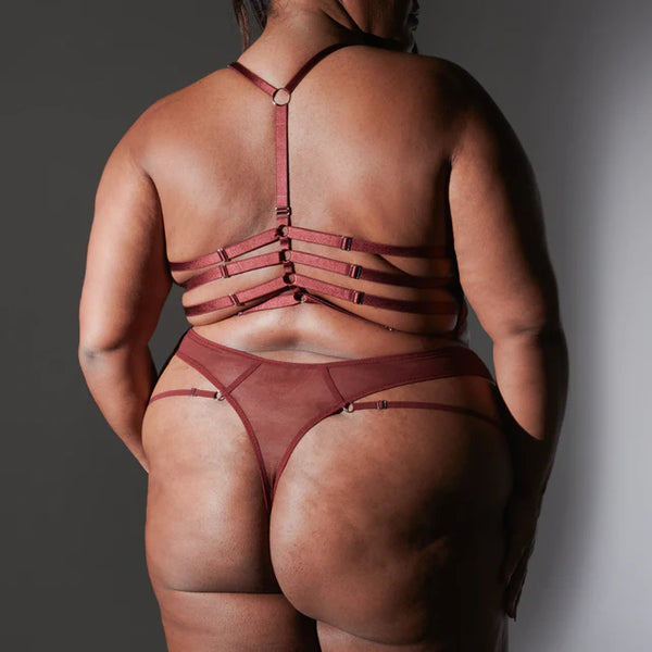 plus size black model shows off the back of the The Sorceress Embroidered Bralette in Oxblood with super strappy straps and a thong back panty