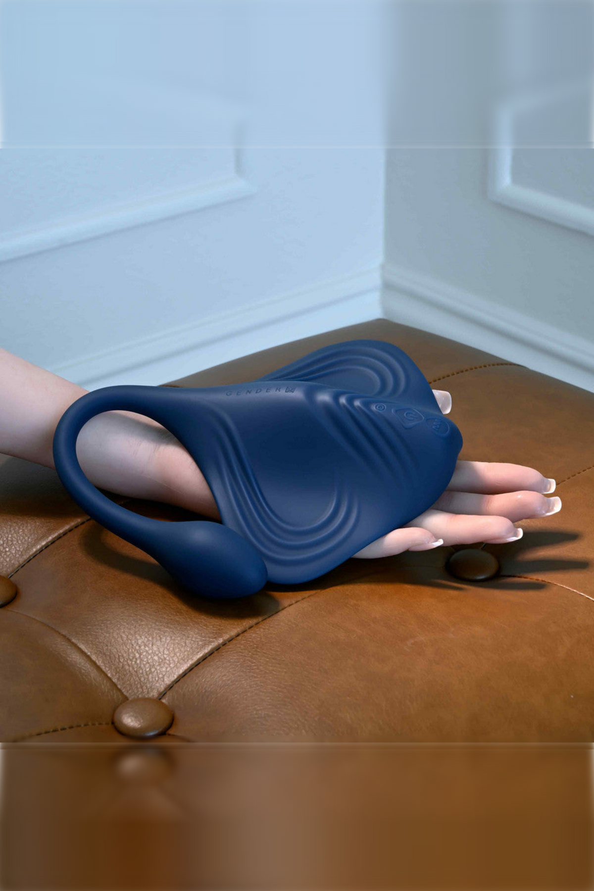Hand slipped under the navy Daily Grind pad on a tan leather ottoman, showing how its wings can wrap around to be used as a stroker
