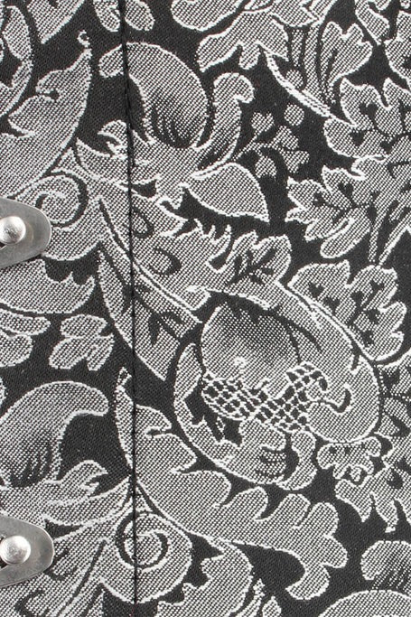 Close-up of the black and silver floral brocade fabric on the Timeless overbust corset, showing the woven leaf pattern and a silver busk clasp