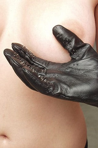 Gloved hand cupping a bare chest, showing the spiked fingers of the black leather vampire sensation play glove in use